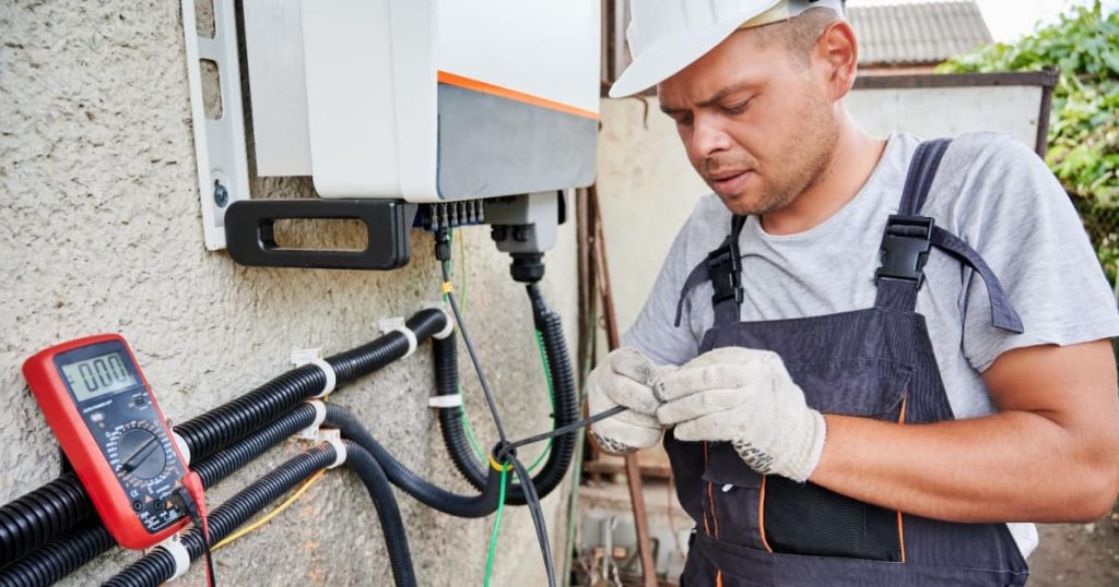 Un installateur professionnel qui s'applique à connecter une batterie domestique au système photovoltaïque