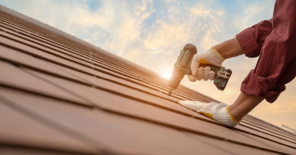 Un couvreur effectuant des réparations sur une toiture en tuiles d'ardoise