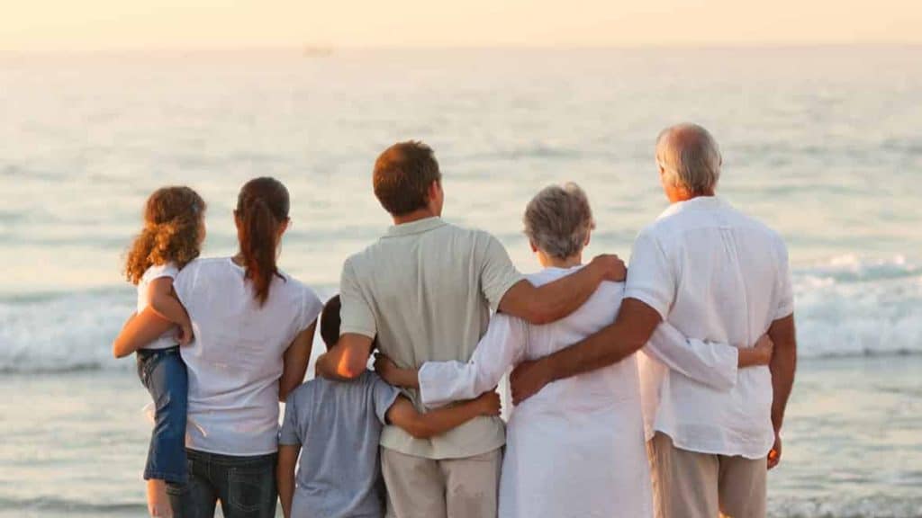une famille toutes générations confondues devant la mer sur la plage