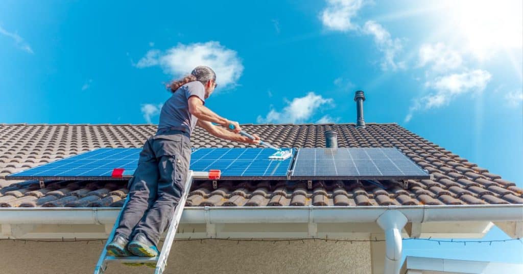 jeune ouvriller entrain de nettoyer des panneaux solaires