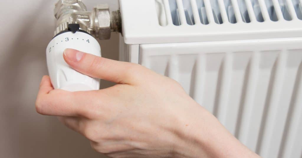 Une main qui tourne le réglage de son chauffage