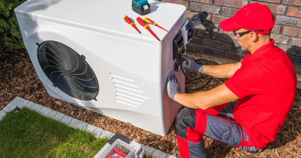 Un technicien habillé en rouge qui installe une pompe à chaleur