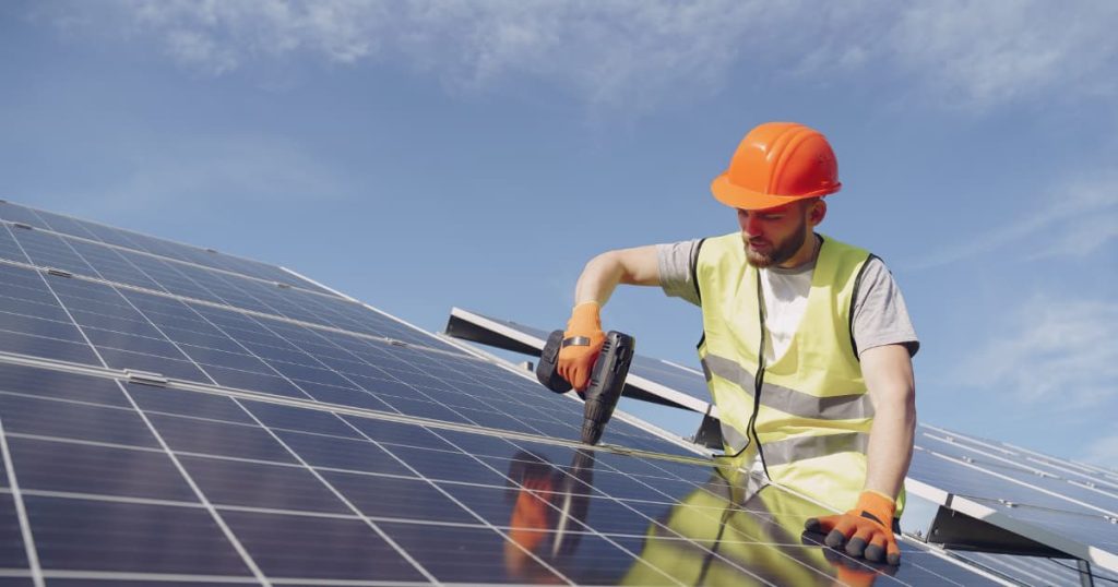 ouvrier entrain de travailler sur des panneaux solaires