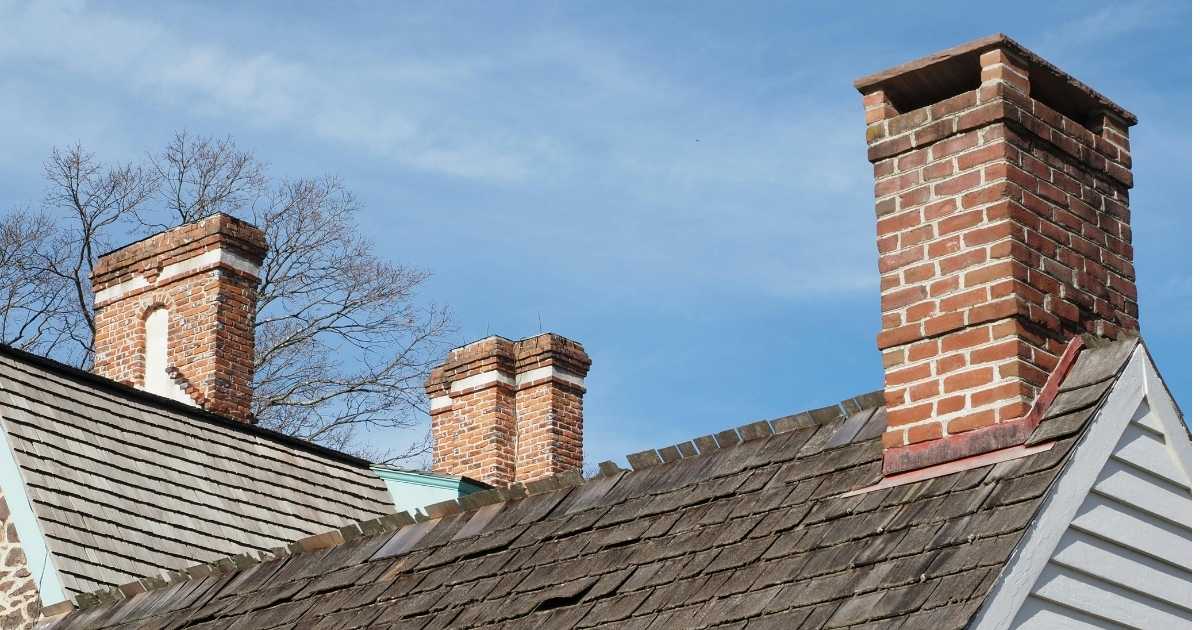 Toiture avec trois cheminées en briques.