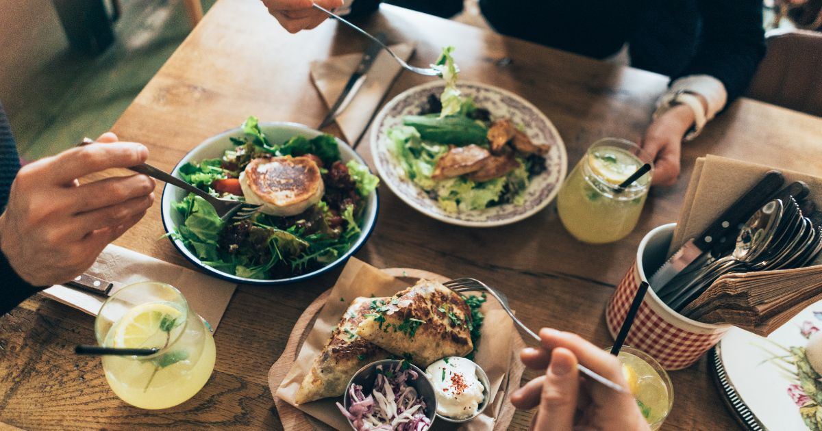 Trois collègues à table dans un restaurant en train de manger des plats sains et de boire une limonade