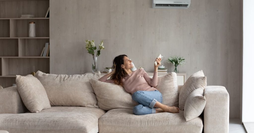 Une femme dans son salon en train de régler la climatisation
