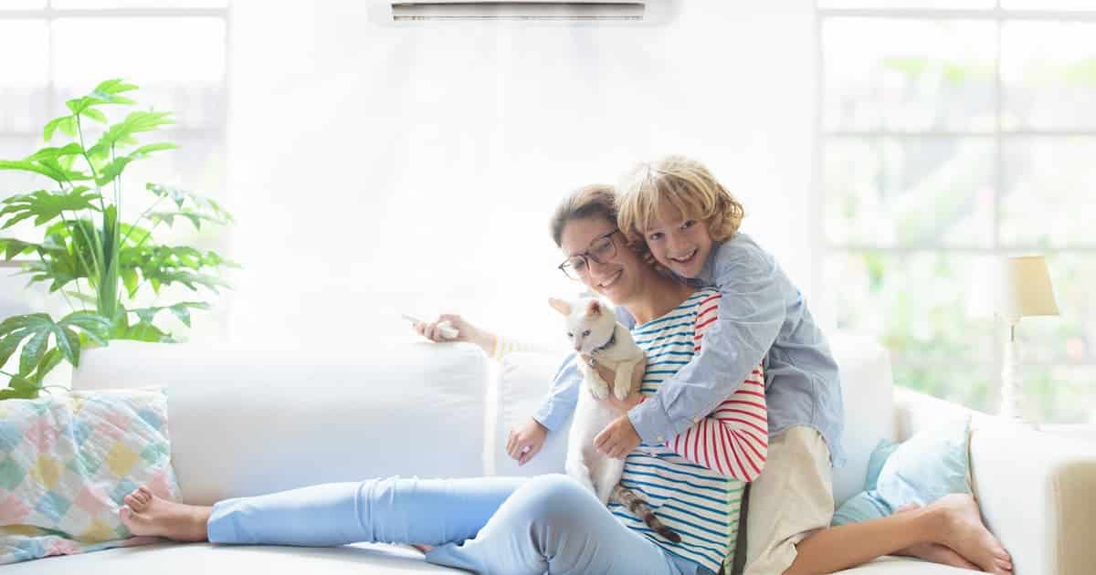 Mère et enfant avec télécommande de l'air conditionné. Température confortable à la maison familiale. Dispositif de refroidissement et de chauffage. Maman et enfant sur un canapé sous la brise froide. Climatisation par beau temps. 