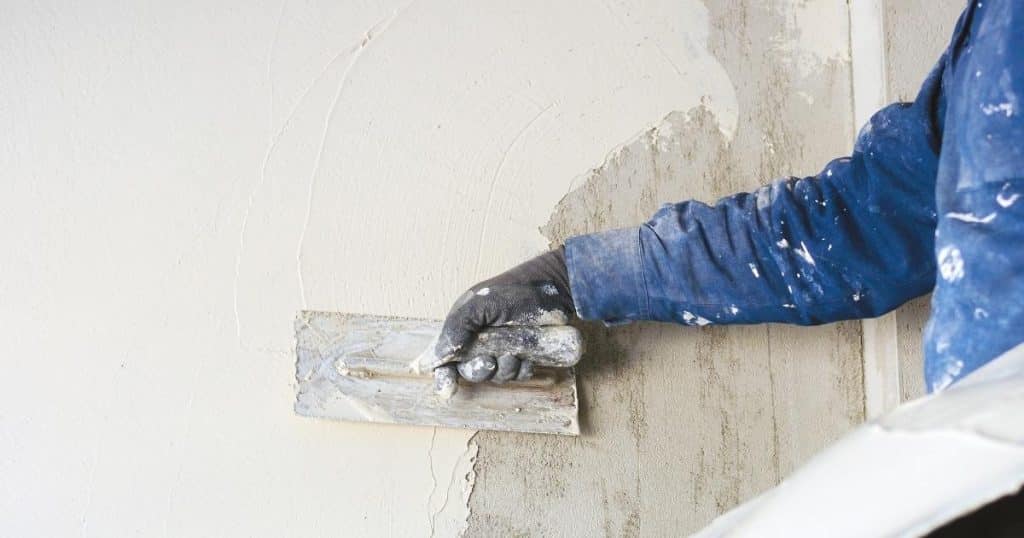 Application d'un crépi sur mur extérieur par un professionnel.
