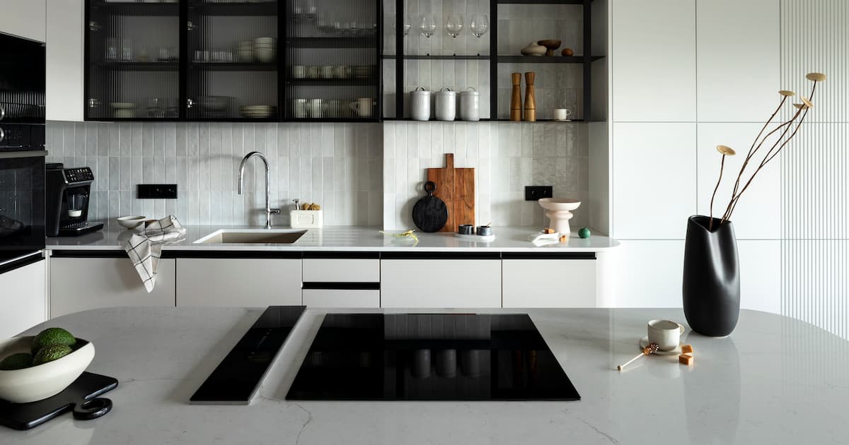 cuisine avec l'île de la cuisine design, table grise, vase noir avec fleurs, meubles et élégants accessoires personnels.
