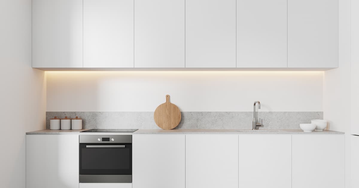 Cuisine intérieure luxueuse et blanche avec évier et poêle, sol en béton gris. 