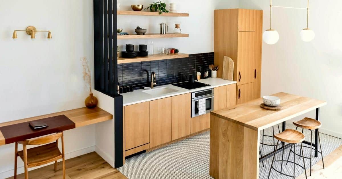 Cuisine avec éléments en bois clair : placards, table, tabourets, frigo