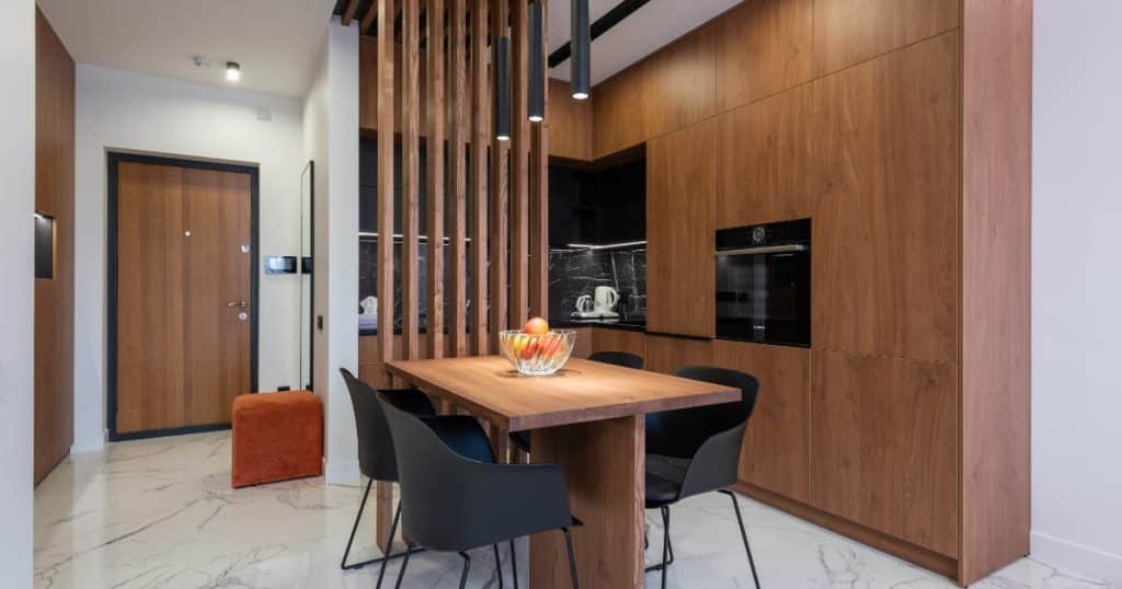 Cuisine en bois moderne avec armoires intégrées, table assortie et cloison en lattes, inspiration design intérieur élégant et chaleureux.