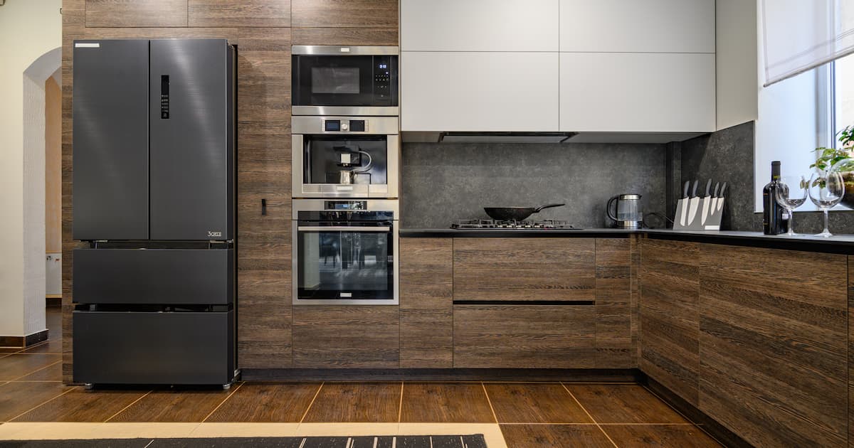 Grand intérieur luxueux de cuisine moderne en L, brun foncé, gris et noir