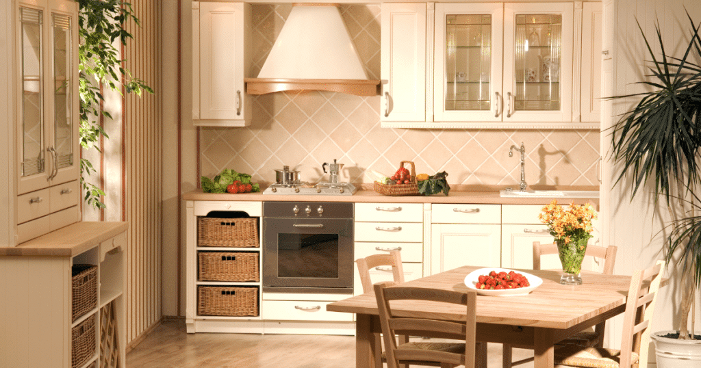 Cuisine rustique et chaleureuse avec meubles en bois clair, paniers en osier, plan de travail en bois, crédence carrelée beige et table assortie décorée de fleurs et de fraises.