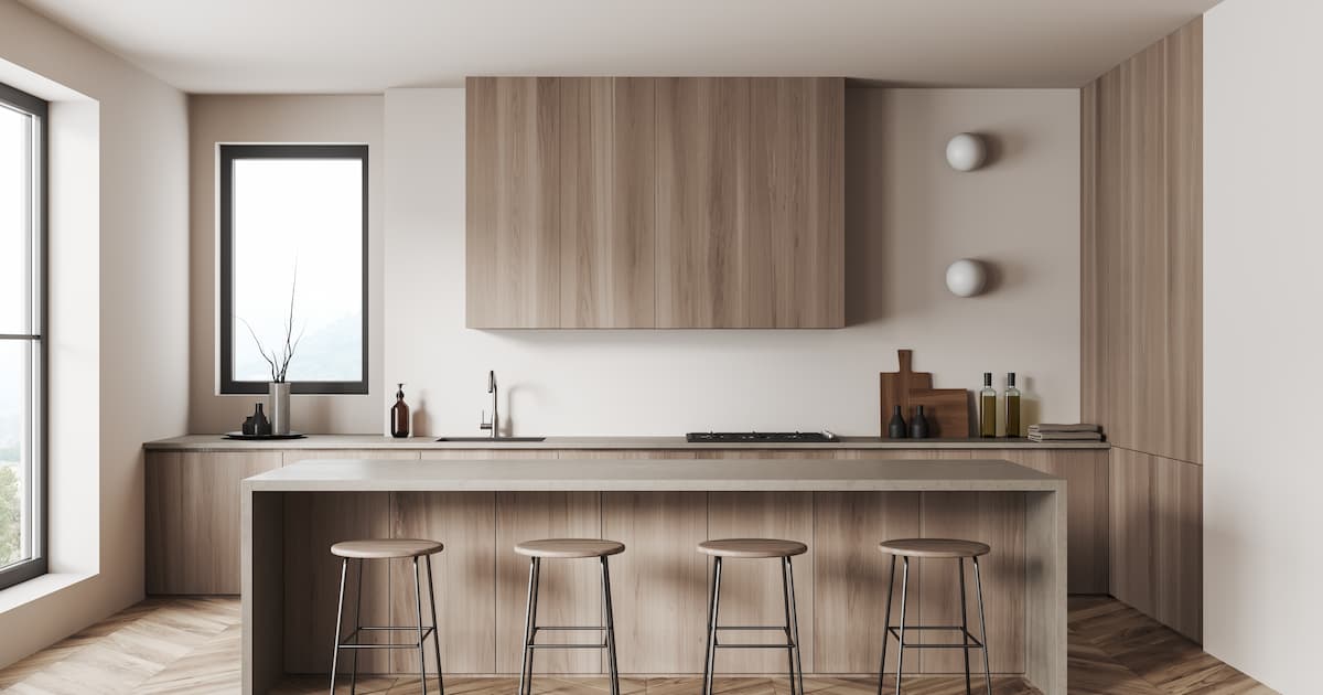 Cuisine beige et taupe à l'intérieur avec tabouret de bar et plan de travail sur parquet.