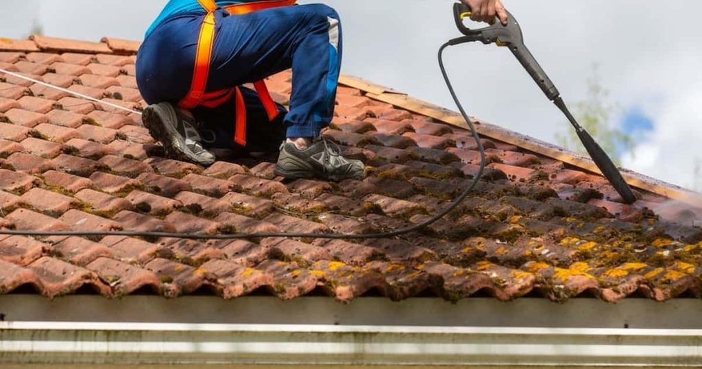 homme accroupis sur une toiture et entrain de la travailler