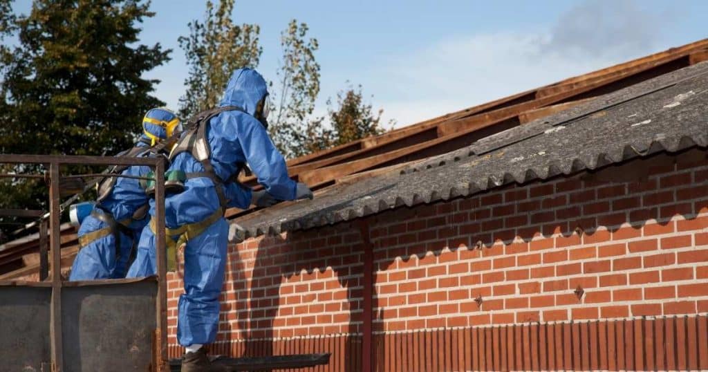 Deux hommes en combinaison bleu en train de désamiantet un toit