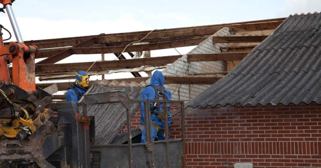 Travaux de désamiantage sur toiture par deux professionnels avec chariot élévateur.