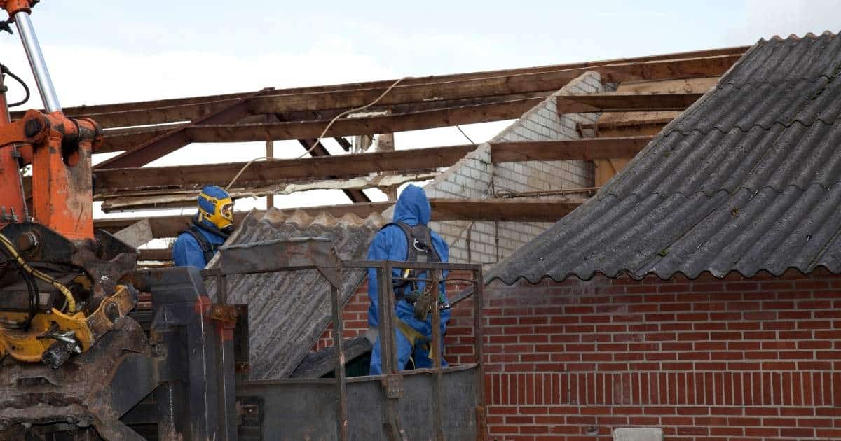 Travaux de désamiantage sur toiture par deux professionnels avec chariot élévateur.