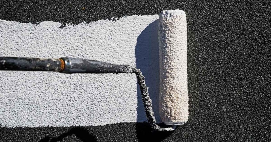 Enduit isolant blanc sur mur gris.