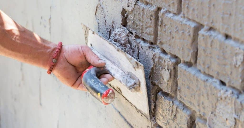 Application d'un enduit isolant sur mur extérieur en briques.