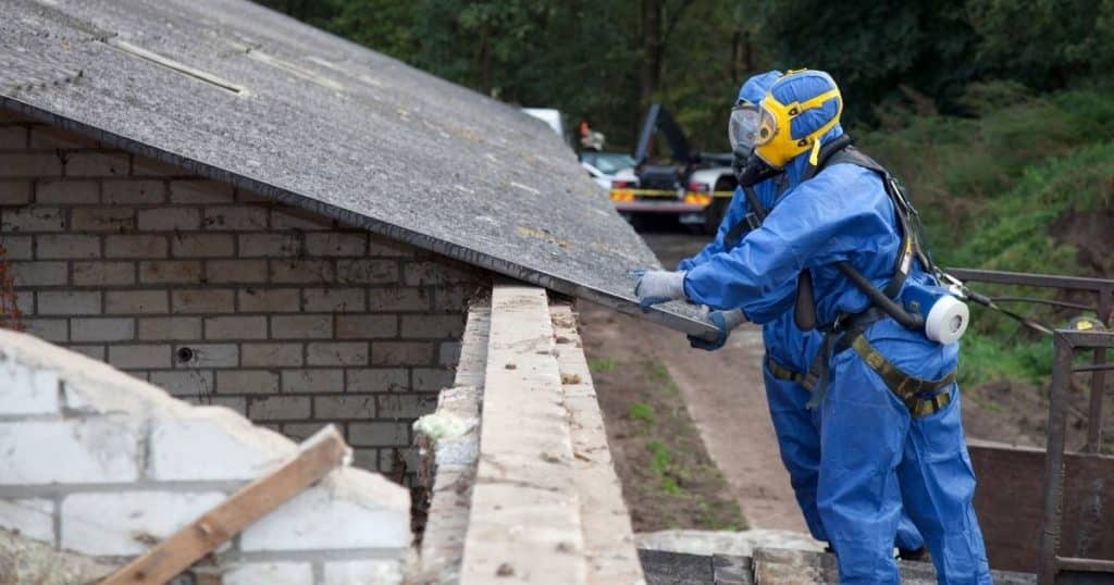 Professionnels réalisant le désamiantage de plaques en amiante sur une toiture.
