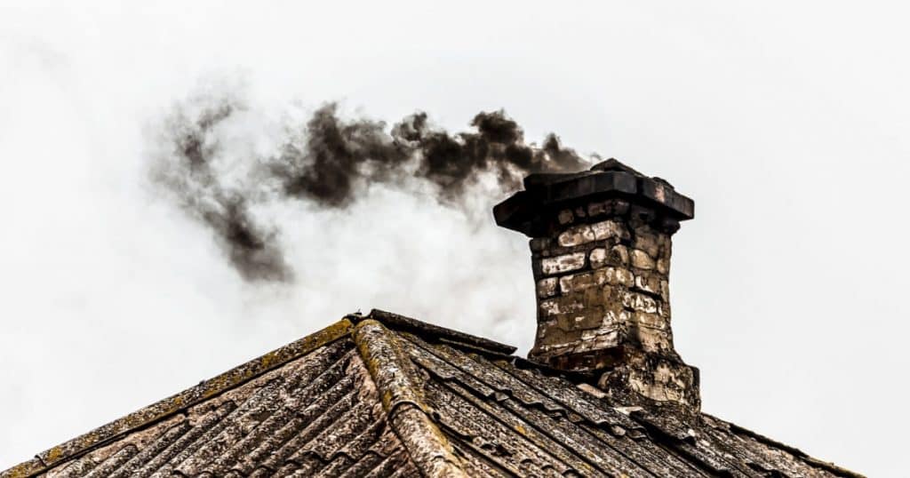 Cheminée dont la fumée est noire et annonce un probable feu de cheminée