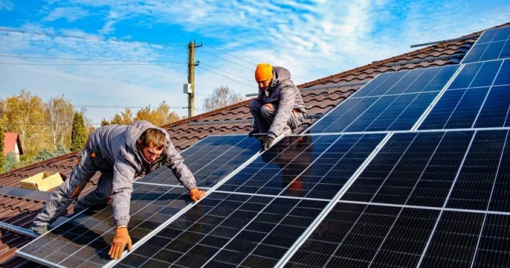 2 installateurs sur un toit installent des panneaux solaires