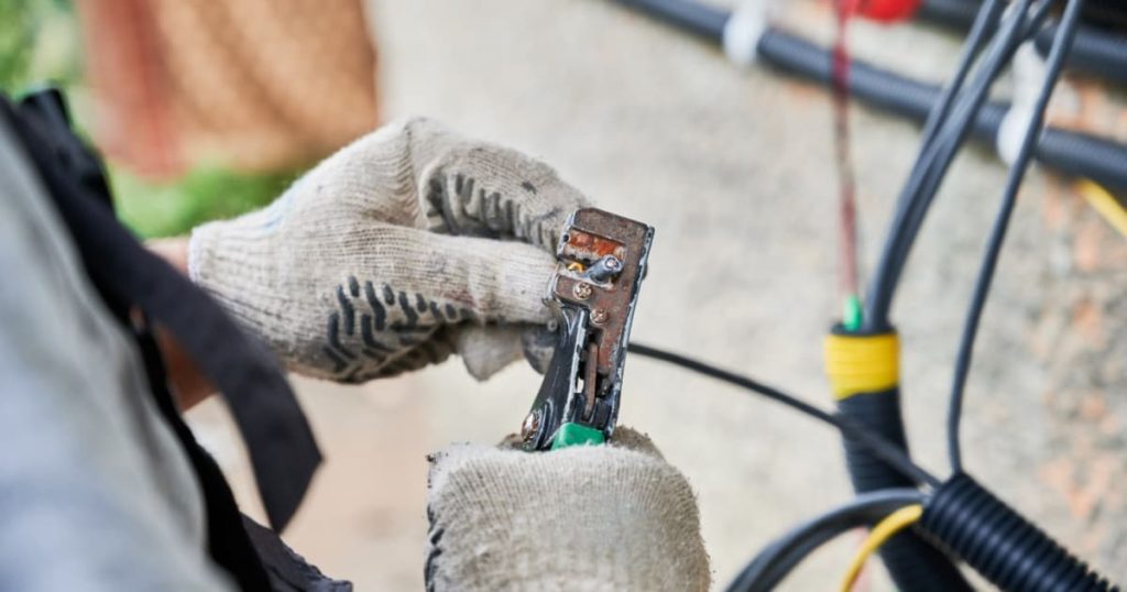 Technicien(ne) qui s'occupe de brancher les câbles d'un panneaux solaires