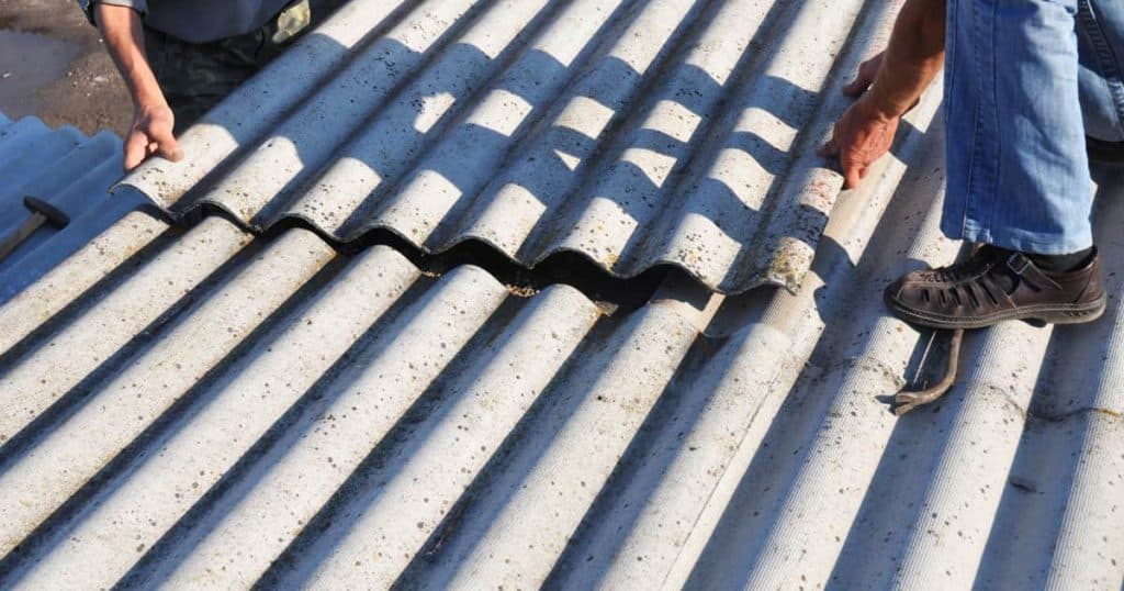 2 hommes en train de retirer les tôles de toiture avec de l'amiante