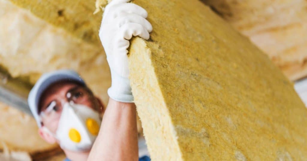 Professionnel effectuant des travaux d'isolation de toiture par l'intérieur avec des plaques d'isolant.