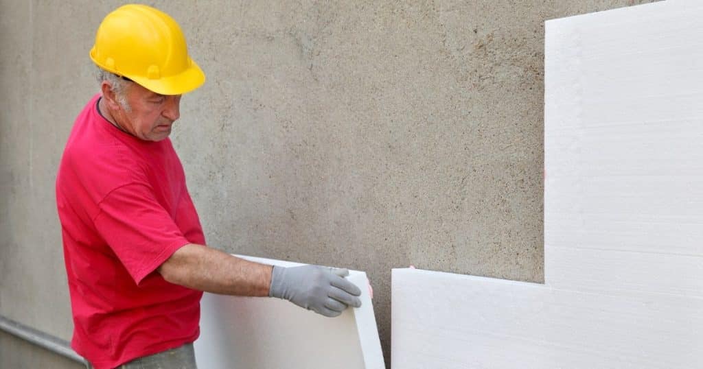 Ouvrier isolant un mur extérieur à l'aide de plaque d'isolant