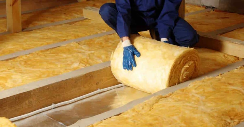 Un homme en train d'isoler phoniquement le sol d'une habitation