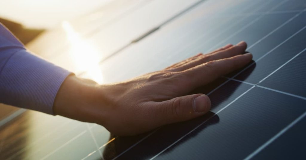 main posée sur un panneau solaire 