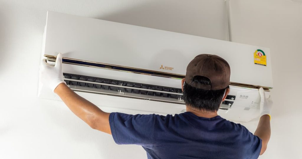 Un homme en train d'installer un climatiseur Mitsubishi