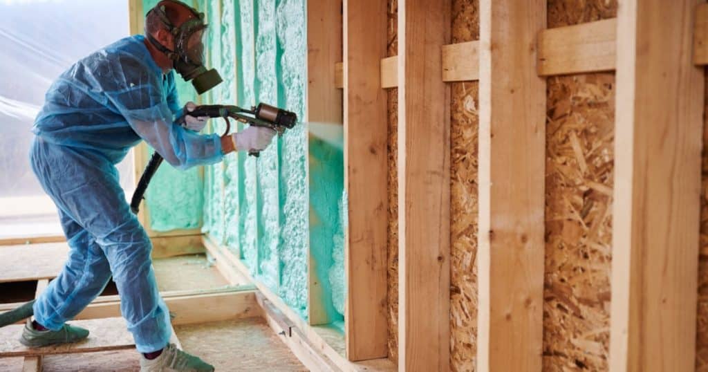 Professionnel projetant mousse d'isolation polyuréthane sur les murs
