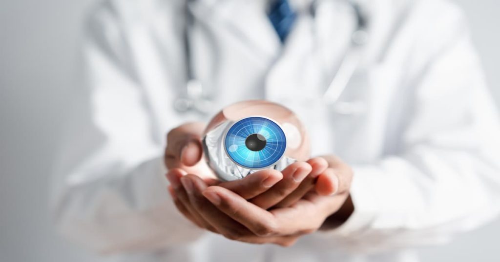 Médecin qui tient un faux oeil dans sa main.