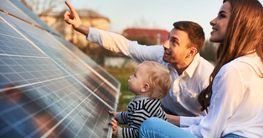 panneau solaire au sol avec une famille qui le regarde le père la mère et le petit garçon