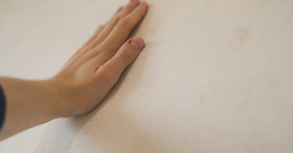 Main posée sur un mur blanc