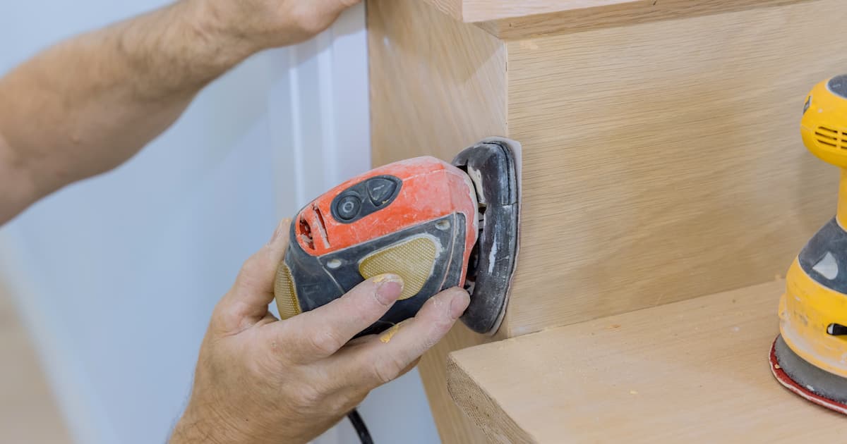 Homme en train de poncer des escaliers en bois