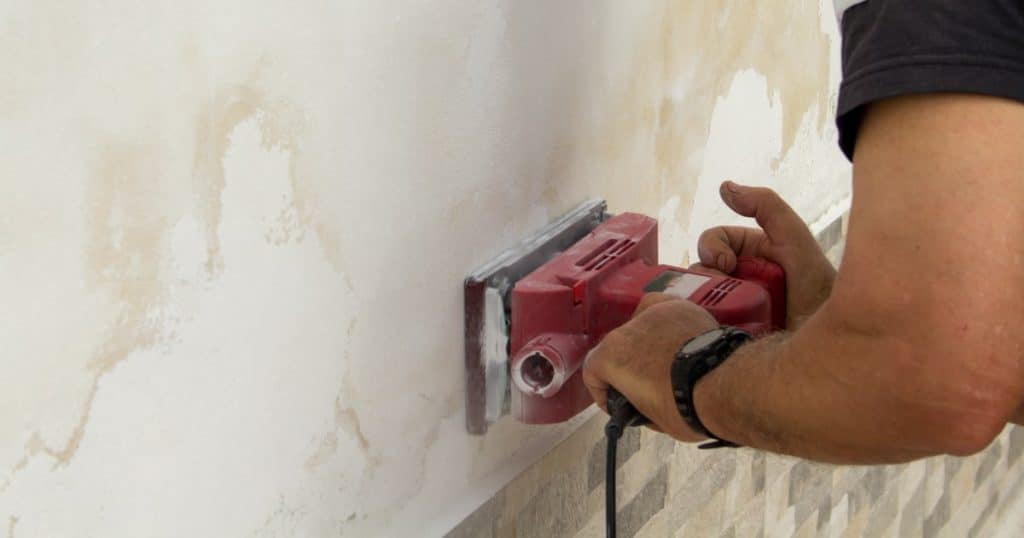 Poncer un mur pour enlever les taches d'humidité