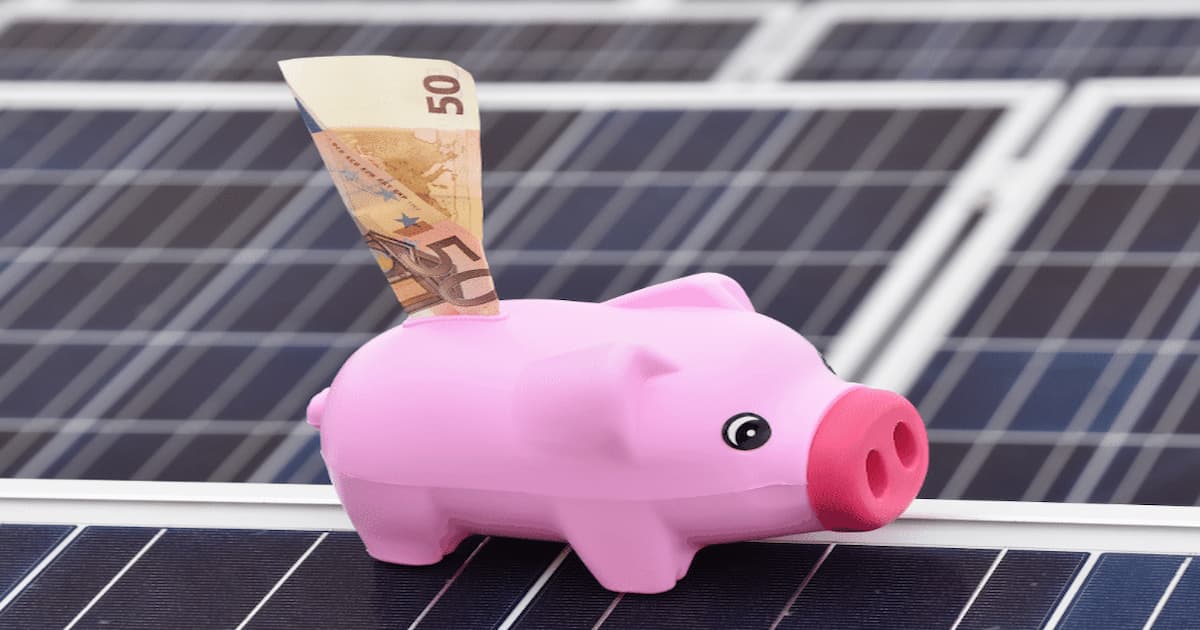 Tirelire sur des panneaux solaires avec un billet de 50 euro inséré dedans illustrant l'économie que l'on fait sur les panneaux solaires avec les primes.