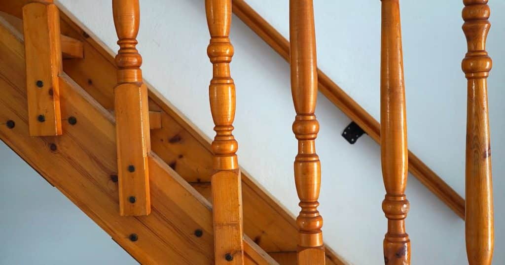 Escalier en bois de sapin menant au deuxième étage avec balustres sculptés. Vue de profil