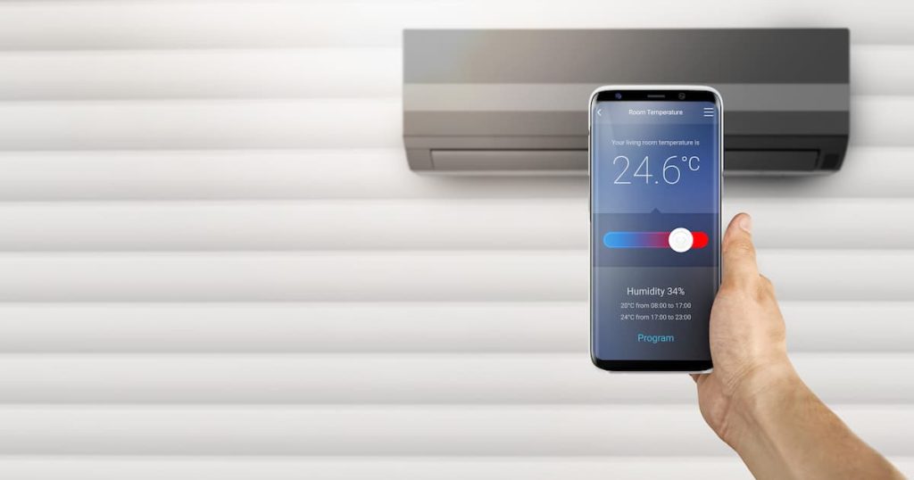 Un smartphone avec SmartThings de Samsung, une application qui vous permet de contrôler votre climatiseur Samsung en réglant la température souhaitée et le taux d’humidité.
En arrière-plan, un élégant climatiseur mural Samsung Windfree noir, un appareil de qualité à un prix équitable.