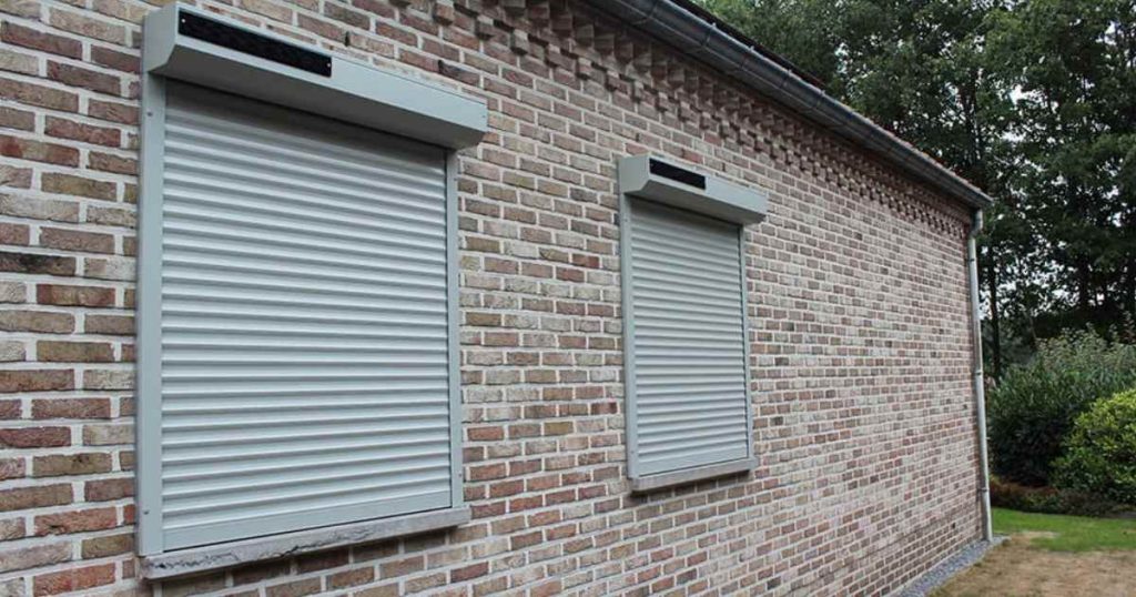 Volet roulant solaire gris installé sur une maison en brique