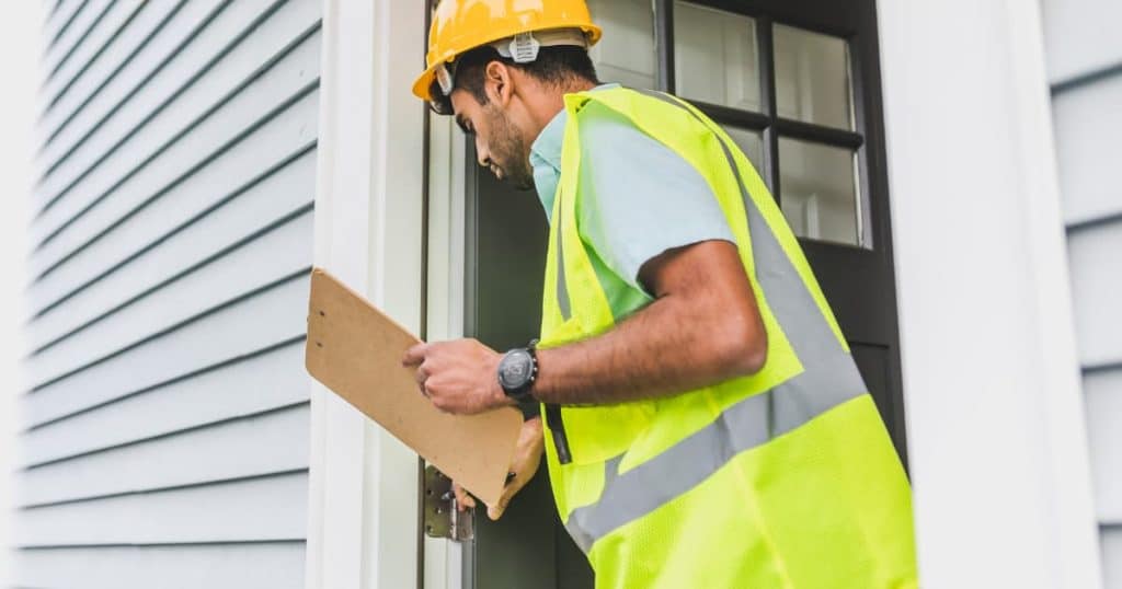 un auditeur avec son uniforme qui inspecte un logement avec un formulaire en main