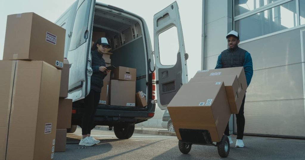 deux personnes qui déchargent de la marchandise d'une camionnette