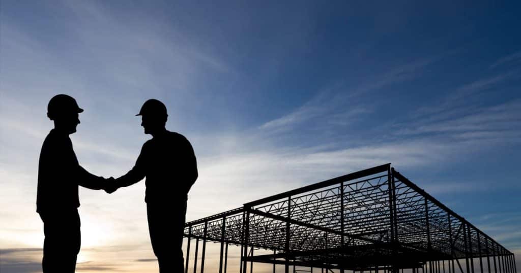 Deux ouvriers se serrent la main dans un chantier en construction 