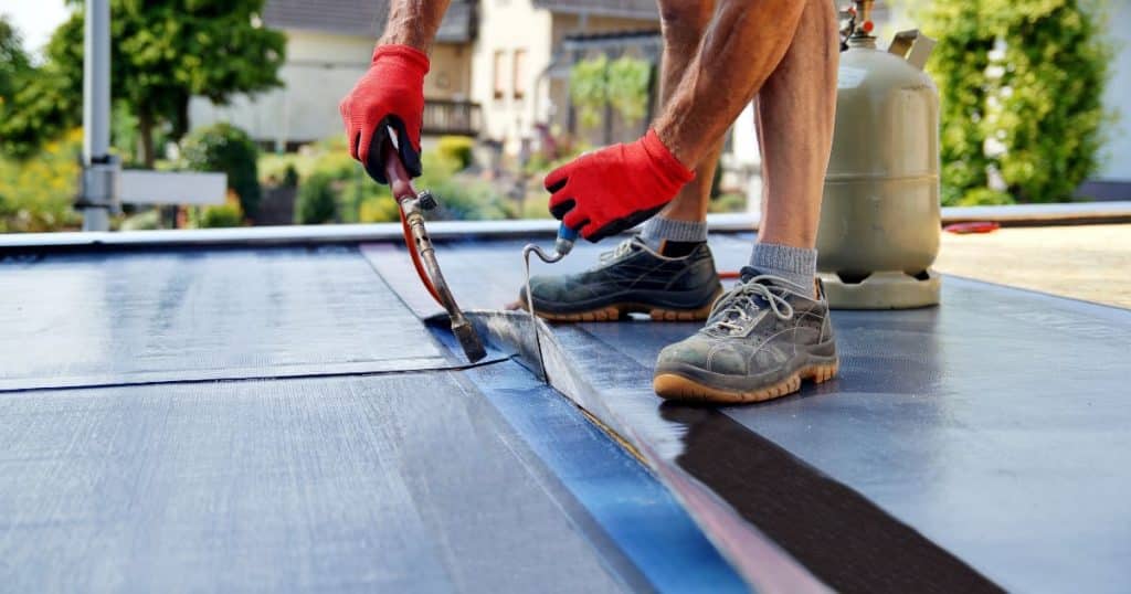 Pose d’une membrane d’étanchéité sur une toiture plate par un professionnel.