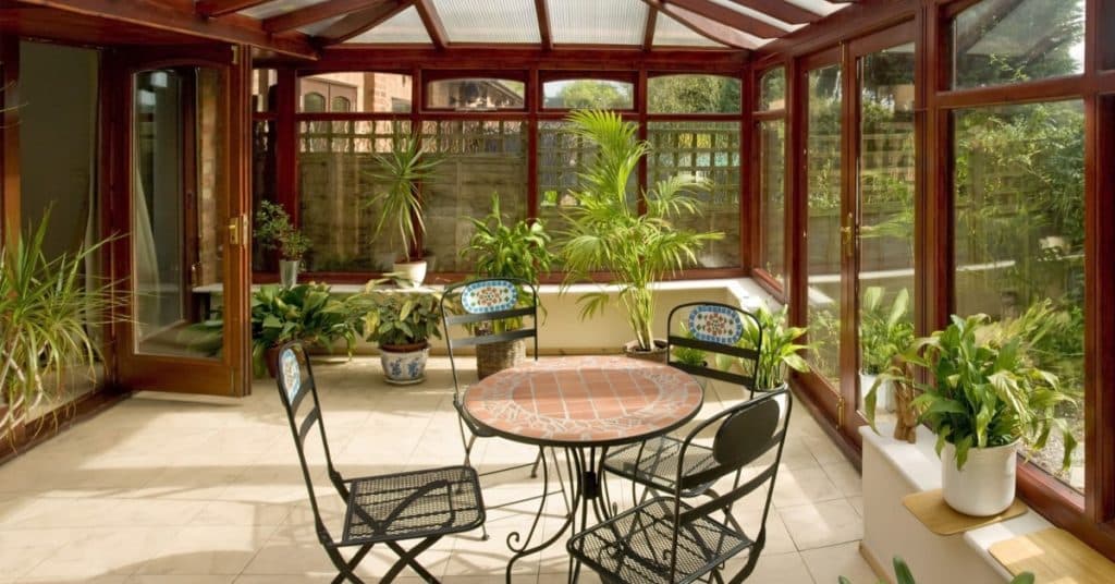 une table 4 chaises et des plantes dans une véranda bioclimatique style ancien 